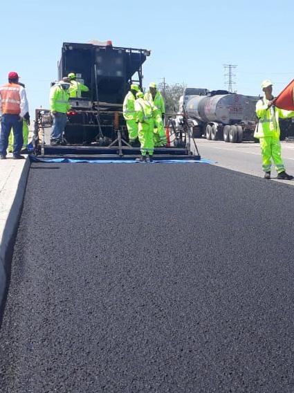 Cuadrilla aplicando microaglomerado en autopista